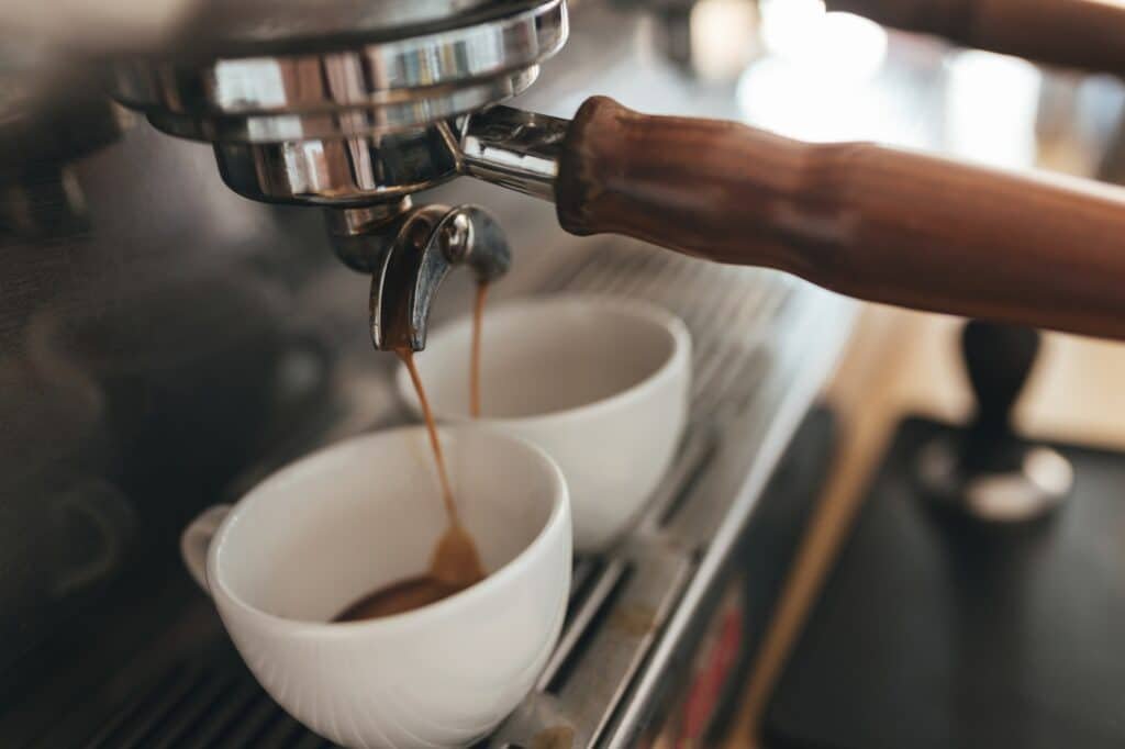 Coffee machine making coffee and pouring into white cups in coffee shop
